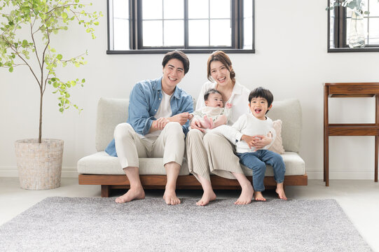 Also in the main visual! A friendly Asian (Japanese) family of four looking at the camera in a newly built-like room in bright sunlight Wide angle