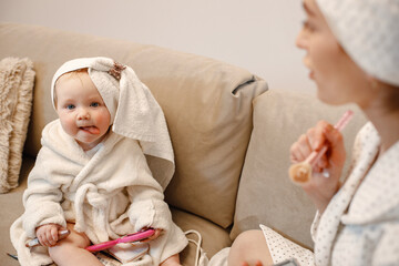 Fototapeta na wymiar Charming mother and little baby daughter with hair wrapped in towels