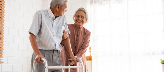 Asian attractive senior woman support elderly man walking with walker. 