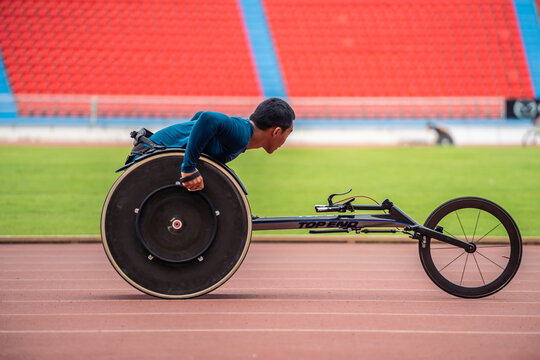 Asian young man para-athletes disabled practice handcycling in stadium. 