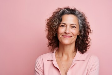 Portrait of smiling mature woman looking at camera over pink background.