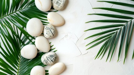 Top view of natural white stones and palm leaves on a white background. Spa background, top view. A tropical summer background for luxury product placement