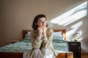 Depressed lonely woman sitting on cozy bed sadly look at window feeling anxiety. Alone girl suffering from emotional pain having life troubles, problems. Mental disorder anhedonia, stress discomfort - obrazy, fototapety, plakaty