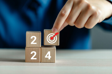 Hand-place wooden cubes with goal icon, Wooden cubes with 2024 and target icon, 2024 goals of a business, starting planning target new year, goal an annual achievement plan.