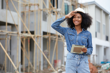 African worker or architect holding tablet and looking to something at construction site