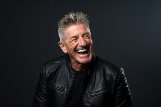Portrait of a happy senior man laughing on a dark background.