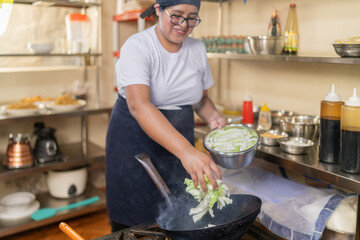 Cook adding vegetables to a frying pan in the restaurant