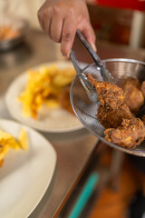 Cook removing breaded chicken from the pan to plate it
