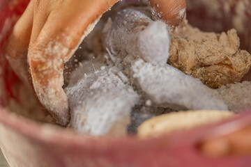Chef's hands mixing flour with chicken for frying