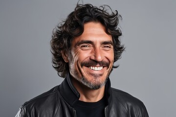 Portrait of a smiling man in leather jacket over grey background.
