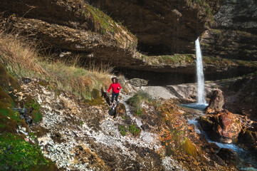 Adult Woman Tourist Trekker Running in Mountains Environment near a Waterfall