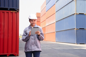 portrait young asian woman standing at terminal port,using digital tablet inspect cargo container, a worker working in shipping yard