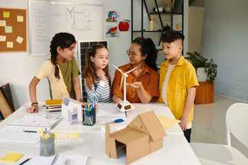 School kids gathered around table with model of small wind turbine