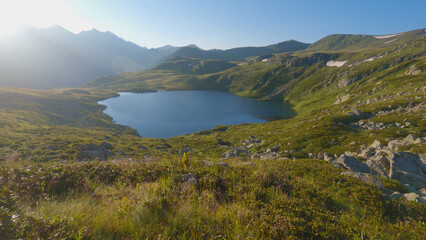 Beautiful blue lake in the mountains amongst rocks and grass. Dawn in the mountains. Hiking in the mountains in summer.