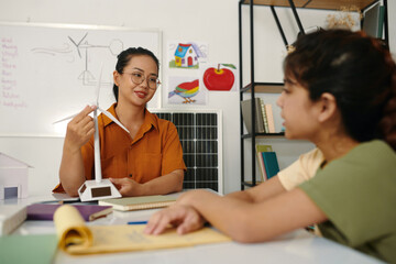 Teacher explaining girl how wind turbine works, learning about sustainability