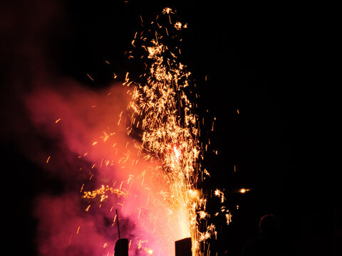 On New Year's Eve, people watch the colorful and bright fireworks at night in a outdoor parking lot in Mosonmagyar&oacute;v&aacute;r, Hungary.