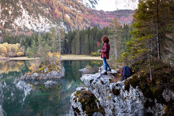 Adventurous Woman Hiker Enjoying a Hot Coffee in Mountains Outdoor Environment Spot near an Alpine Lake