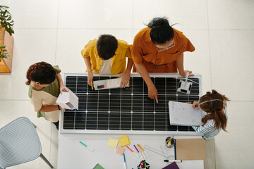 Teacher and schoolkids discussing solar energy and sustainability living, top view