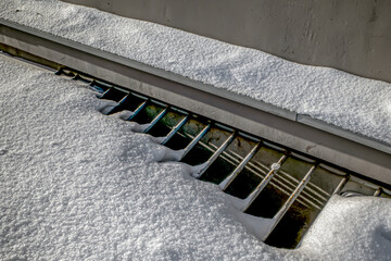 A snow-covered basement window on a winter day