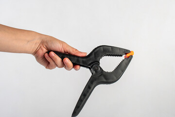 Obraz premium Black plastic spring clamp in hand isolated on black background