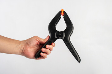 Black plastic spring clamp in hand isolated on black background