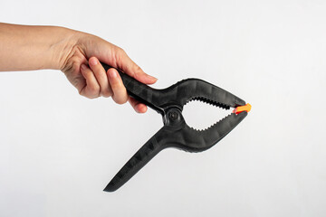Obraz premium Black plastic spring clamp in hand isolated on black background