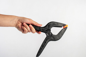 Black plastic spring clamp in hand isolated on black background