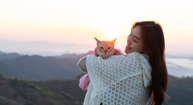 Travel concept with a pet.Cute asian girl on the mountain hugs her bengal cat.young woman with a cat on the mountain in morning