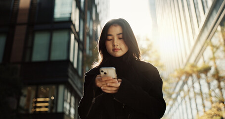 Walking, phone and Japanese woman in the city networking on social media, mobile app or the...