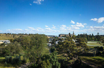 Fototapeta na wymiar Elevated view of the suburb of Sunbury with trees and heritage buildings in the distance. Melbourne VIC Australia. It is on the outskirts of Melbourne's urban fringe, considered a satellite township.