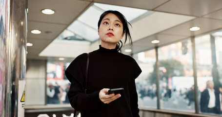 Phone, subway and a Japanese woman in city on social media, networking and notification in Tokyo. Smartphone, girl and serious person on mobile communication technology, thinking and internet app - obrazy, fototapety, plakaty