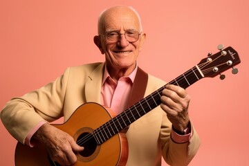 Portrait of an elderly man playing the guitar on a pink background