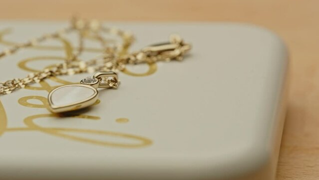 Pan past a beautiful golden necklace with a stunning locket on the lid of a jewelry box