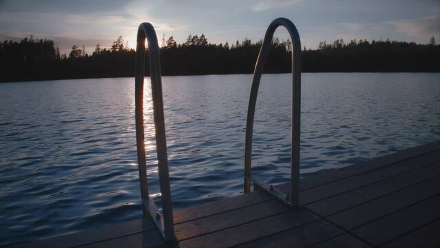 Ladder on a swimming pier during sunset in a Swedish lake