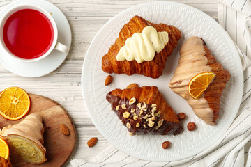 Fresh croissants with cup of tea on table