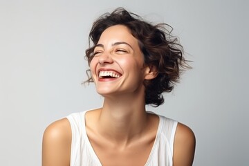 Portrait of a happy young woman laughing and looking up on gray background