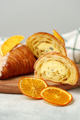 Glazed croissant with dried orange on wooden board
