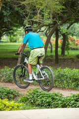 Fototapeta na wymiar old man on a bike going through a park doing sports