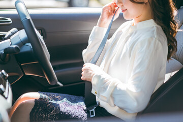 車に乗り込みシートベルトをする女性ドライバー（交通ルール・安全運転・交通安全）
 - obrazy, fototapety, plakaty
