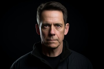 Portrait of a serious mature man looking at the camera on a black background