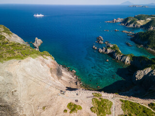 青い海と緑の森が美しい神引展望台から見る、沖を航行する大型客船（さるびあ丸）と中の浦海水浴場、神引浦の空中ドローン撮影。

東京都伊豆諸島新島村式根島にて。
2023年11月4日撮影。

Aerial drone shot of a large passenger ship (Sarubia Maru) sailing offshore, Nakanoura Beach, and Kamihiki