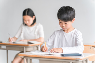 学校の教室で勉強する小学生の男の子（塾・夏期講習）
