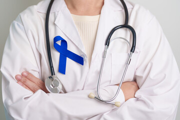 March Colorectal Cancer Awareness month, doctor with dark Blue Ribbon for supporting people living and illness. Healthcare, hope and World cancer day concept - obrazy, fototapety, plakaty
