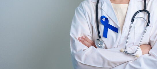 March Colorectal Cancer Awareness month, doctor with dark Blue Ribbon for supporting people living and illness. Healthcare, hope and World cancer day concept