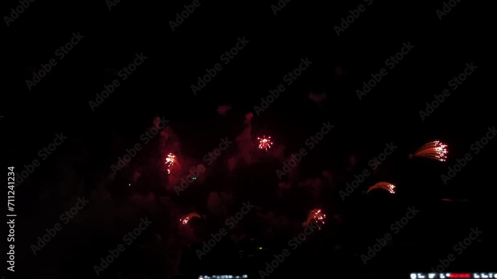 Poster cameras lined up in a row in front of a pyrotechnic display at a beachfront during a fireworks festi