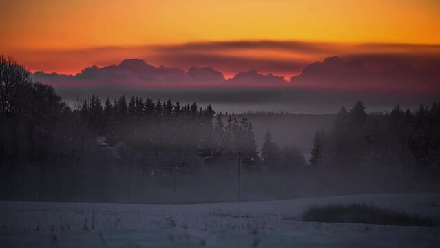 Colorful timelapse from sunset to dark over foggy snow meadow.