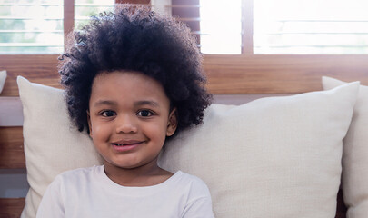 Portrait young happy little afro black boy rest on sofa living room background. Education back to school spend leisure time at home, authentic carefree smile happily looking at camera with copy space