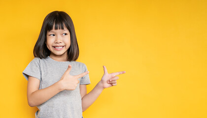 Portrait of young fun smart happy little cute asian girl isolated on yellow background with copy...