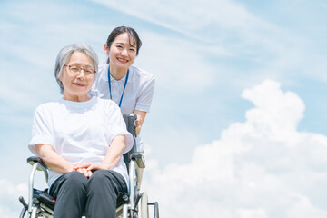 青空と介護福祉士・介護士と高齢者・シニア女性・おばあちゃん
