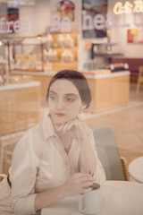 Young Caucasian Female portrait in coffee shop holding a cup of coffee
